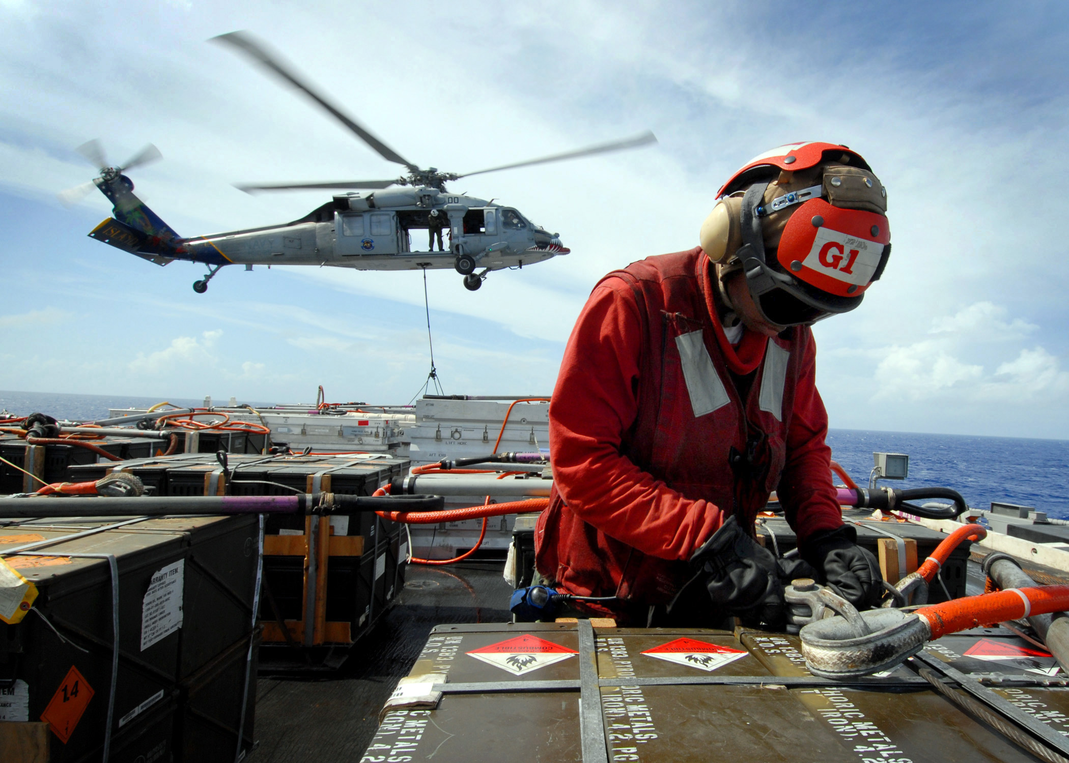 US Navy 081107-N-1038M-115 Aviation Ordnanceman Airman Jessica Jefferson attaches cables to a crate of ammunition as an MH-60S Sea Hawk