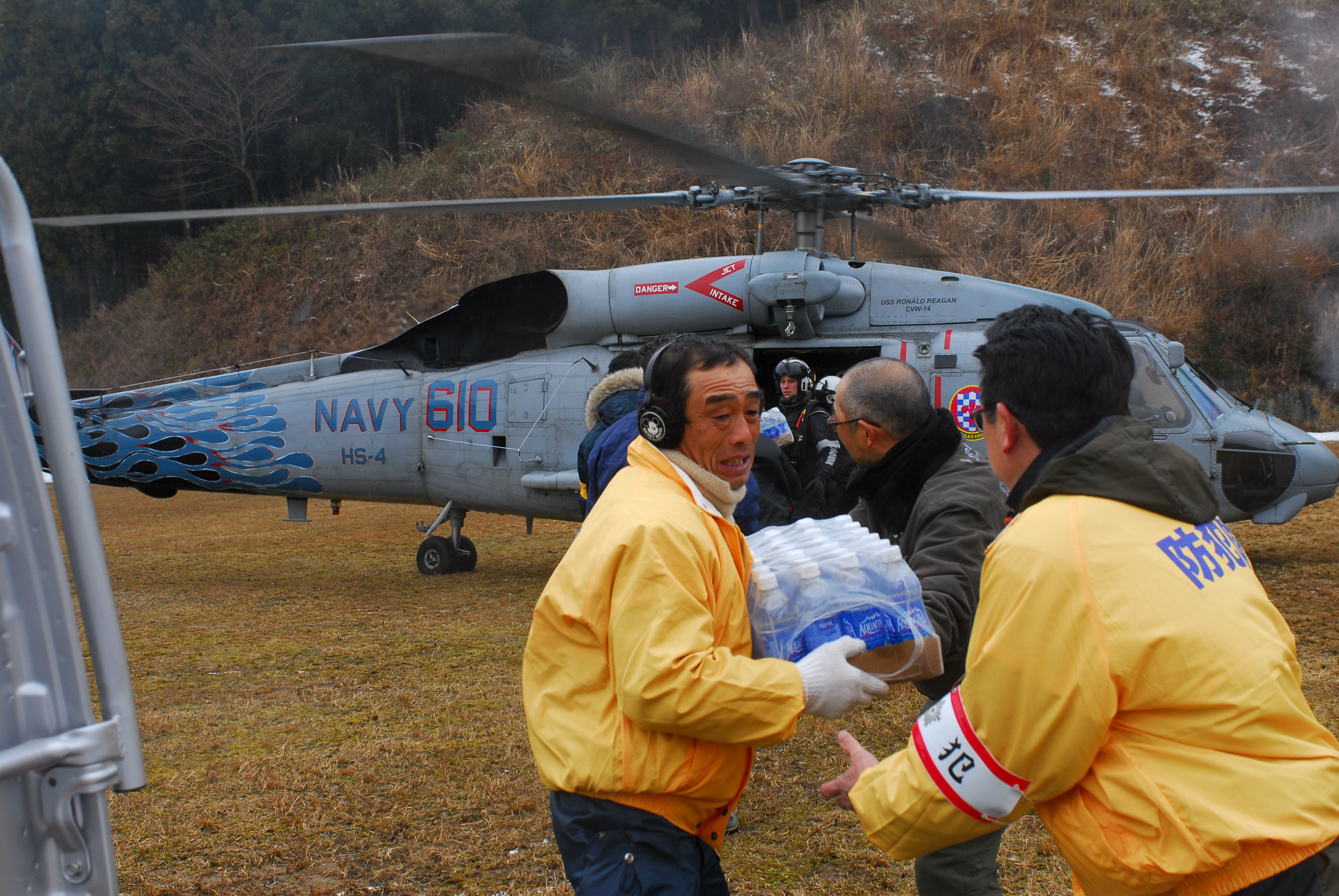 US Navy 110316-N-SB672-114 Japanese citizens unload food and water from an HH-60H Sea Hawk helicopter assigned to the Black Knights of Helicopter A
