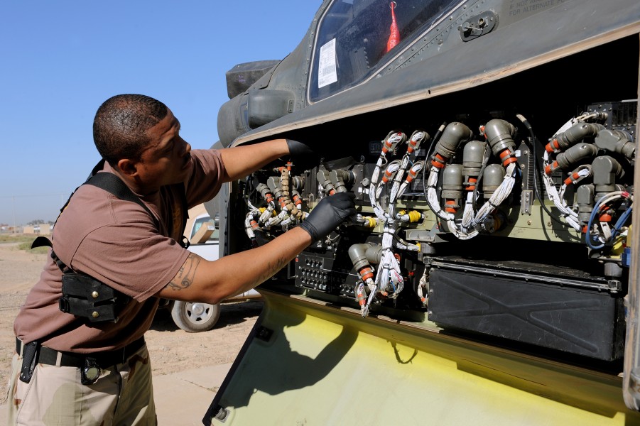 US Navy 100415-F-5214M-005 Petty Officer 2nd Class Lavonderick Campbell, a Navy customs administrator, inspects behind a front panel of an AH-64 Apache helicopter at Joint Base Balad, Iraq