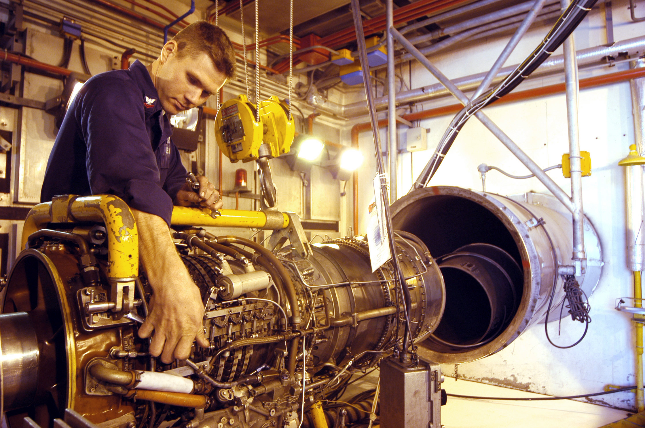 US Navy 030321-N-9693M-006 Aviation Machinist's Mate 2nd Class David Lyman, left, tightens a fitting on a T-64 turbo shaft engine for an MH-53E 'Sea Dragon' helicopter