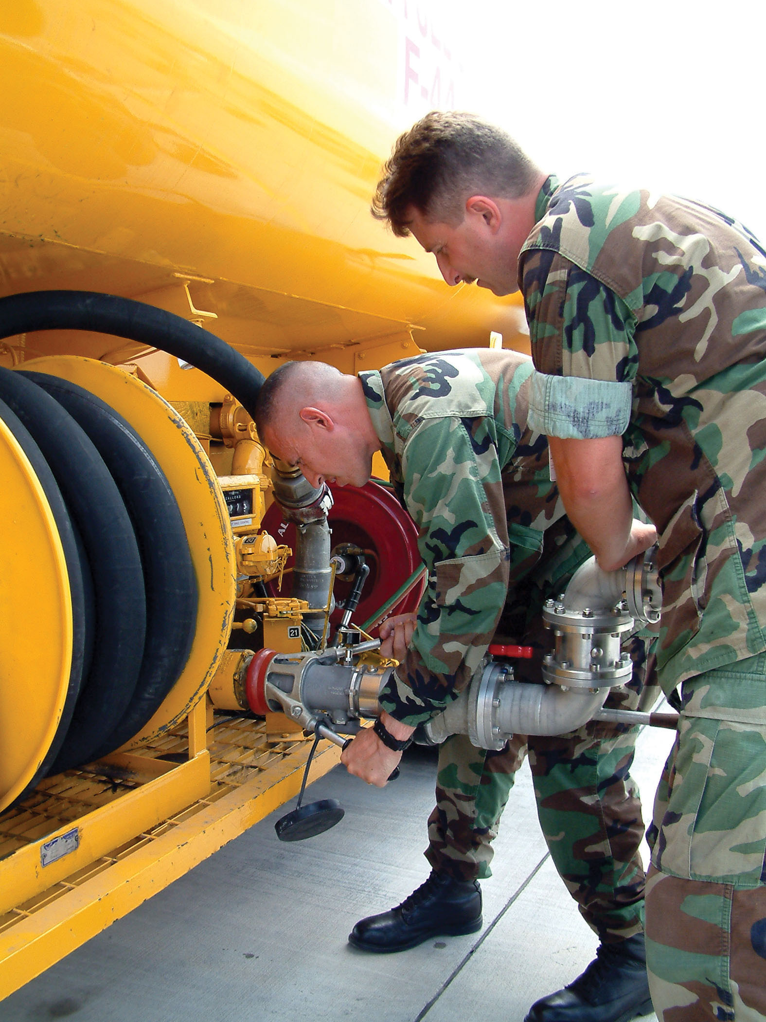 US Navy 030620-N-5821W-003 Lt. Cmdr. Timothy Dudley and Aviation Boatswains' Mate 1st Class Ron Howton connects a nozzle to a 5,000 gallon refueling tanker on the NAS Sigonella flight line