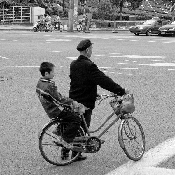 A man is holding cycle with kid