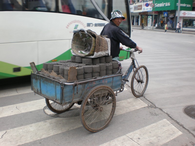 Man transporting charcoal at Minzhu Road intersection, Lijiang