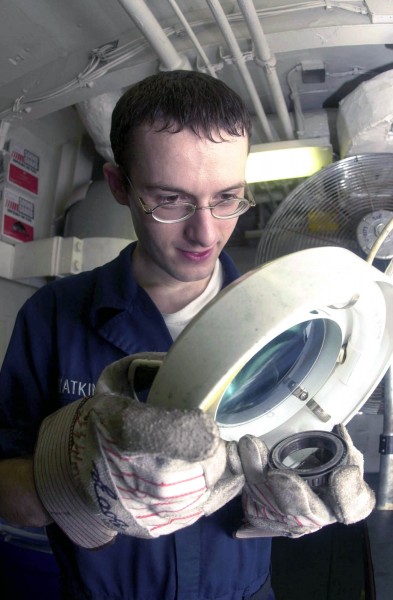 US Navy 030903-N-2143T-001 Aviation Structural Mechanic Airman John Watkins uses a magnifying glass to check for defects