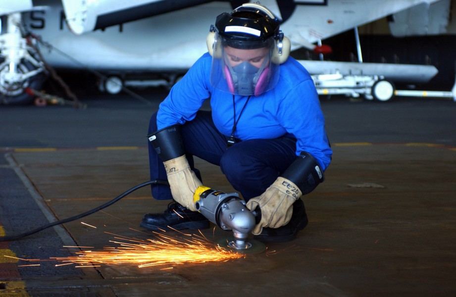 US Navy 040604-N-9319H-027 Airman Carmeia Wetchie, from Firth, Idaho, grinds non-skid from a weapons elevator door