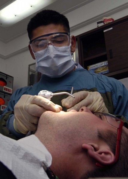 US Navy 040824-N-5384B-056 Dental Technician 3rd Class Carlos M. Valverde, of Nicaragua, performs a routine semi-annual checkup and cleaning on the teeth of a Sailor