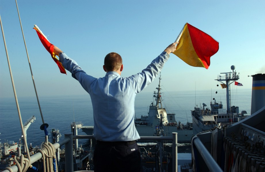 US Navy 051129-N-0685C-007 Quartermaster Seaman Ryan Ruona signals with semaphore flags during a replenishment at sea
