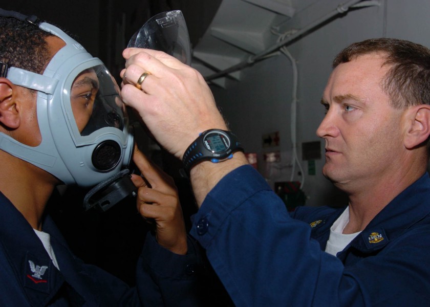 US Navy 060127-N-9641C-002 Chief Damage Controlman, John Brooks, removes the face shield from a Sailor^rsquo,s MCU-2-P gas mask