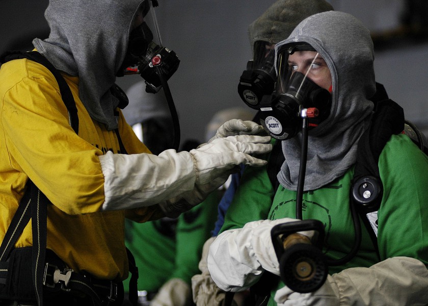 US Navy 060315-N-5837R-055 A nozzle man listens to the scene leader for instructions on battling a simulated fire in the hangar bay