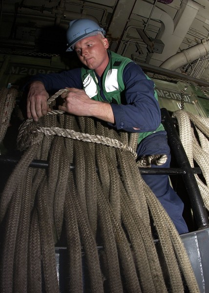US Navy 070130-N-5567K-005 Boatswain^rsquo,s Mate 3rd Class Trent Shuler of Dolan Springs, Ariz., coils and stows mooring lines used for Landing Craft Air Cushion operations in the well deck
