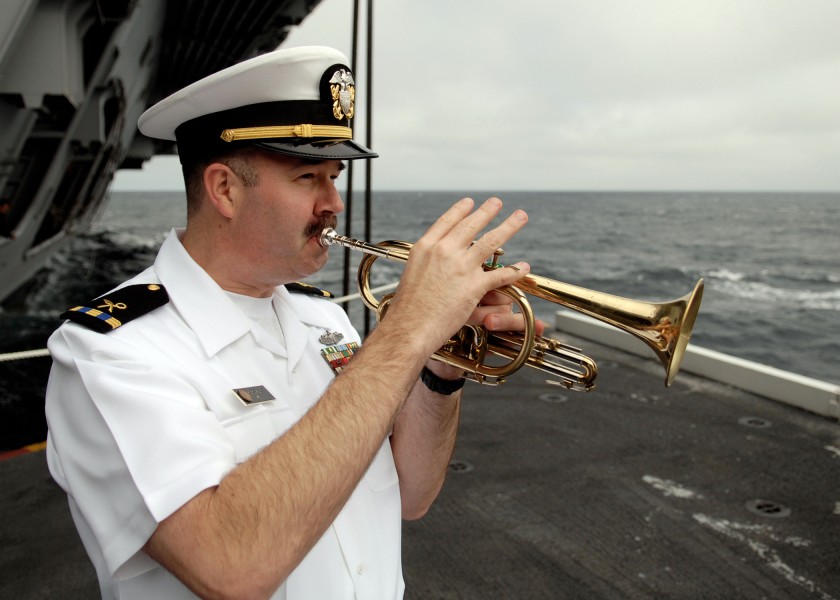 US Navy 070819-N-7981E-122 Chief Warrant Officer 3 Rob Holland plays taps at the completion of a burial at sea ceremony aboard Nimitz-class aircraft carrier USS Abraham Lincoln (CVN 72)