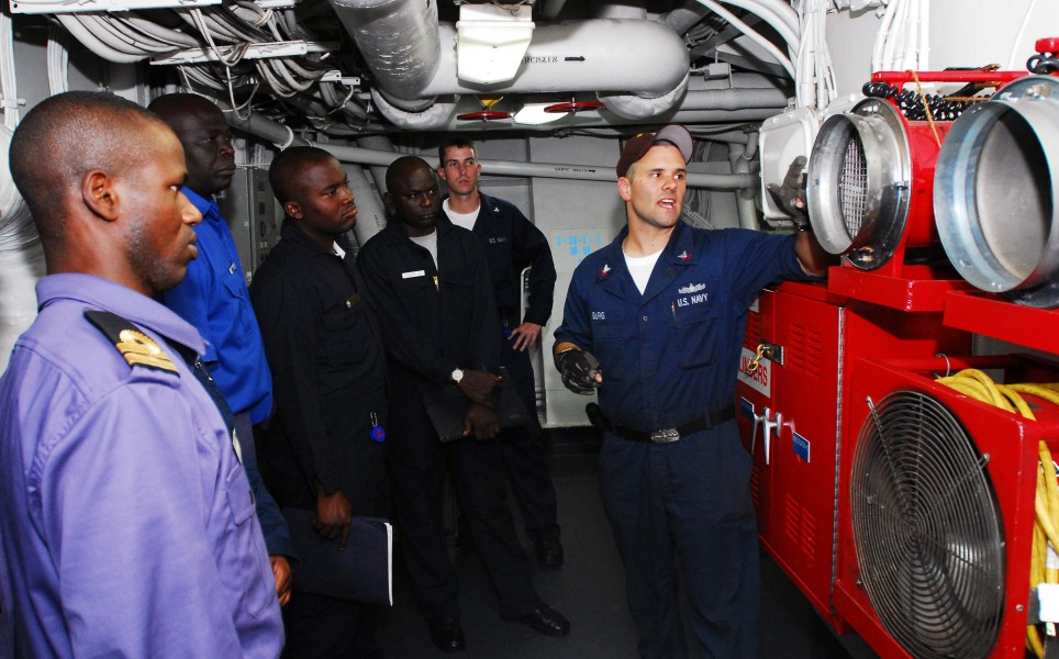 US Navy 071101-N-8933S-015 Damage Controlman 2nd Class Adam Burg talks about the Ram Fans used to remove smoke from an area after a fire is extinguished to Nigerian Sailors