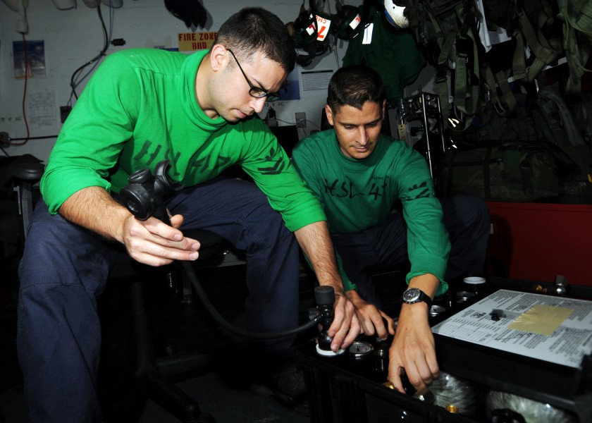US Navy 080627-N-9898L-020 Aircrew Survival Equipmentman 2nd Class Joe Quintero, left, and Aircrew Survival Equipmentman 1st Class Brian Hawks fill emergency breathing bottles for survival vests