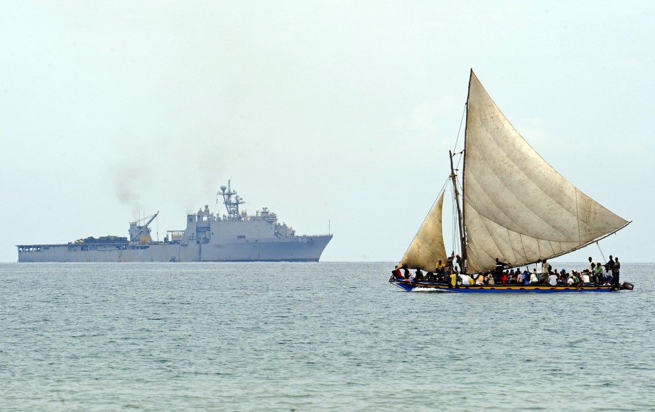 US Navy 100119-N-5345W-110 A Haitian boat sails off the coast of Haiti as the amphibious dock landing ship USS Carter Hall (LSD 50) operates in the distance