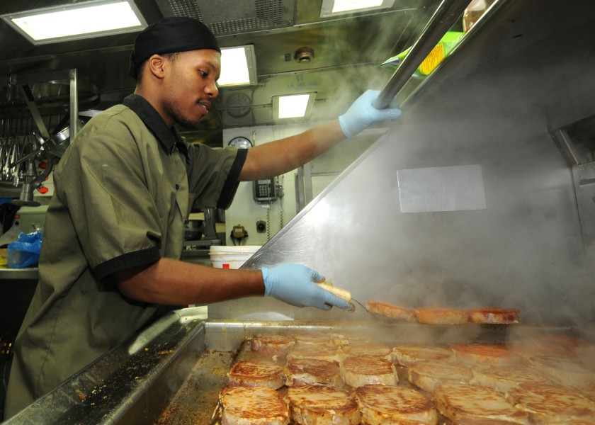 US Navy 110124-N-9793B-024 Culinary Specialist Seaman Diante A. Johnson prepares pork chops in the ship's galley