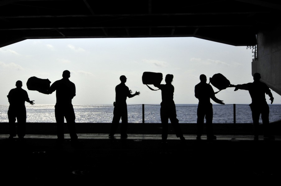 US Navy 110414-N-DM338-087 Sailors pass chemical, biological and radiological kits during a working party in the hangar bay of the aircraft carrier