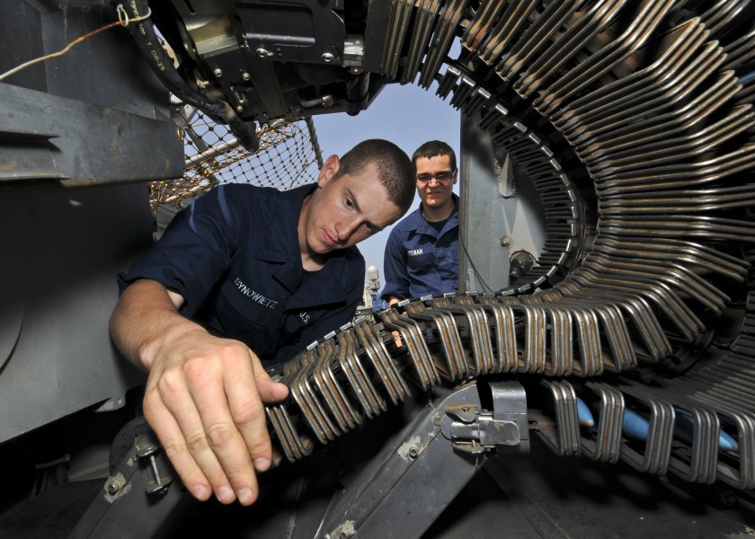 US Navy 110618-N-YM590-079 Gunner's Mate Seaman Ryan Synowietz performs maintenance on a MK-38 25mm gun system aboard the guided-missile cruiser US