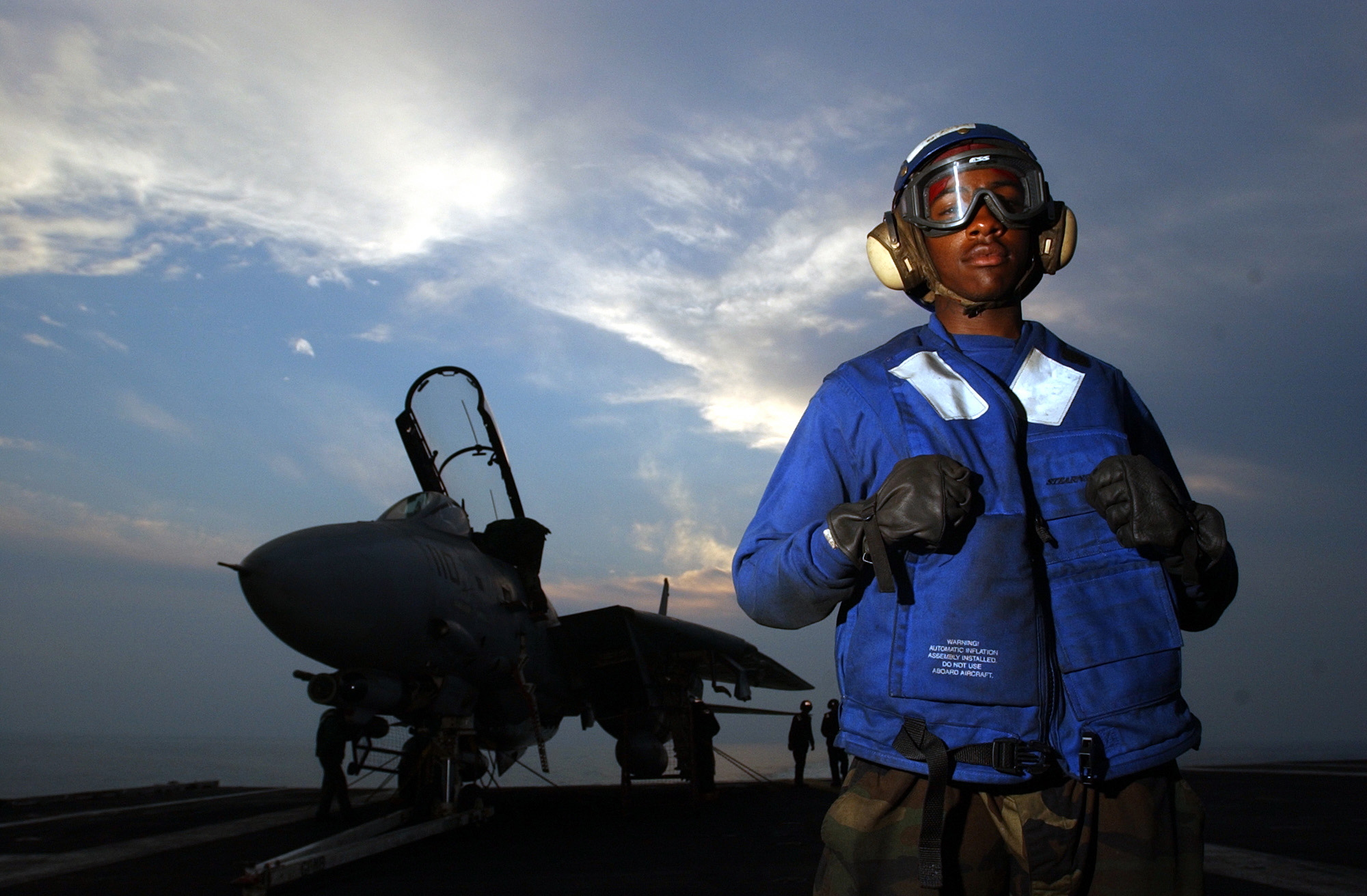 US Navy 021031-N-4309A-017 Flight deck crew aboard the nuclear powered aircraft carrier USS Abraham Lincoln (CVN 72), watches the sun set as they wait for night flight deck operations to begin