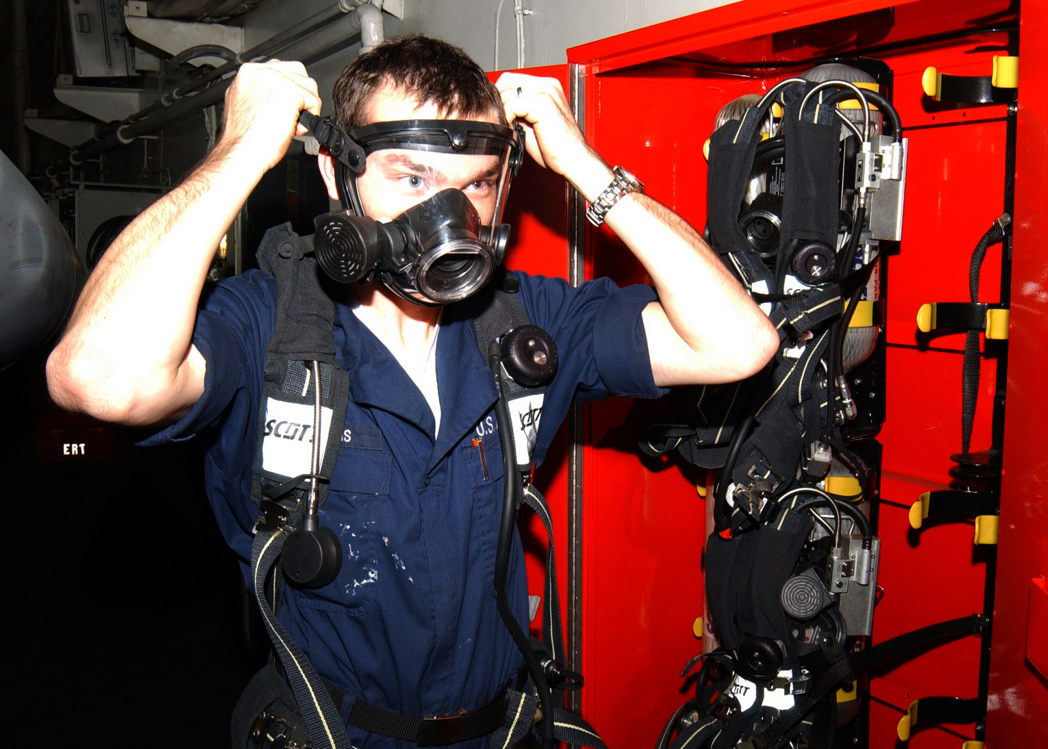 US Navy 021102-N-6817C-005 Damage Controlman Fireman Aaron Williams, of Amarillo, Texas, checks for the proper fit on a face mask on a Self Contained Breathing Apparatus (SCBA)