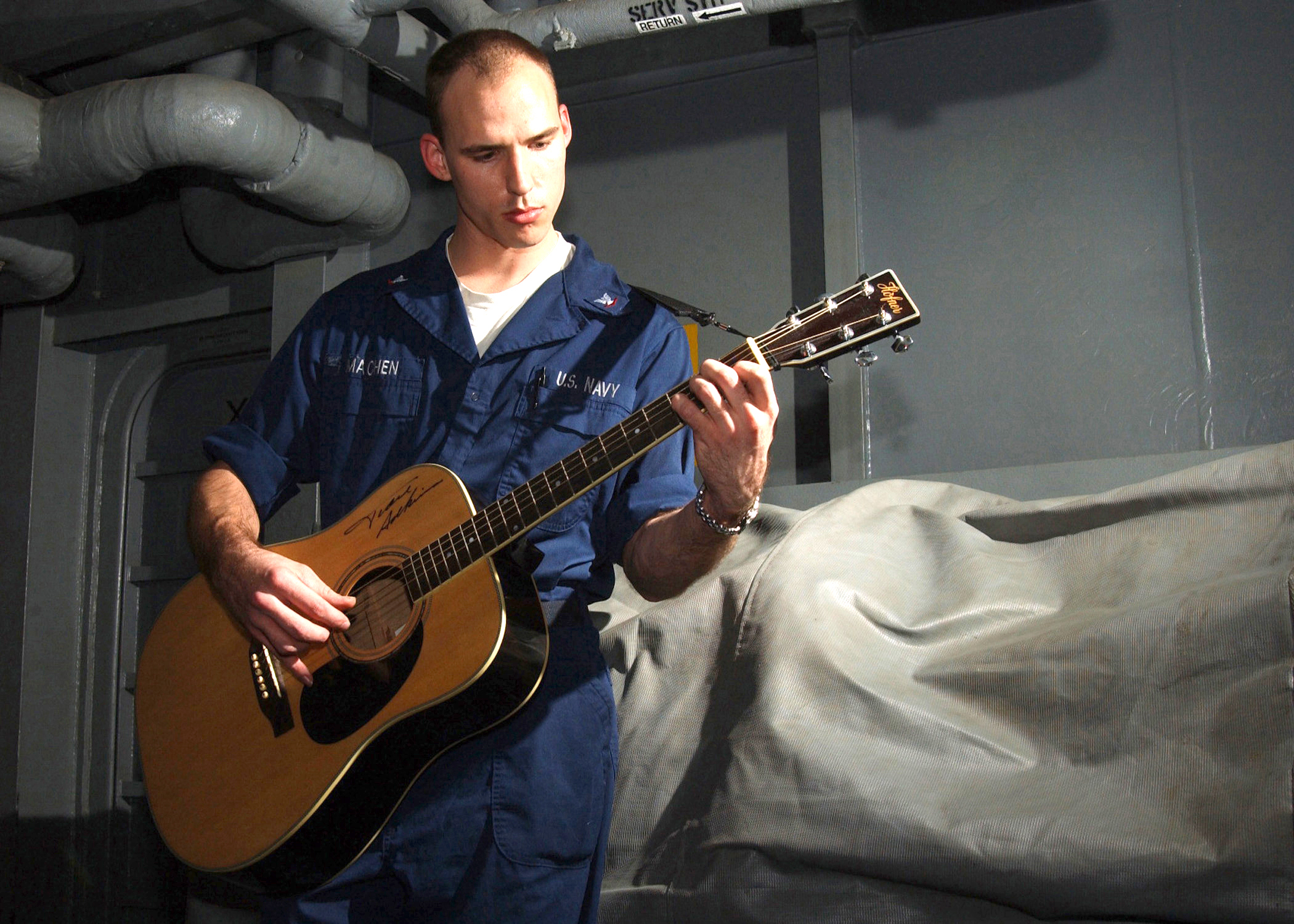 US Navy 021201-N-6817C-001 Sailor enjoys playing his guitar during some leisure time aboard the aircraft carrier USS Abraham Lincoln (CVN 72)