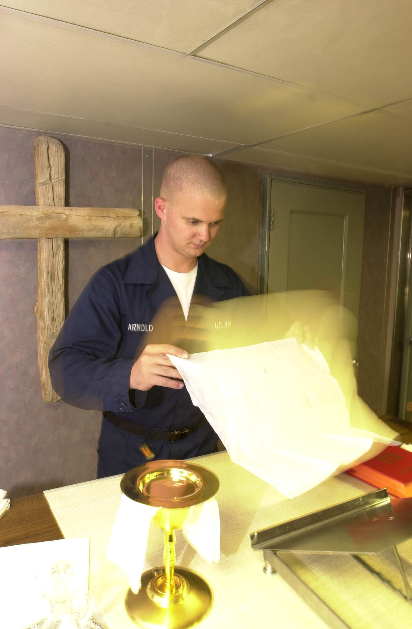 US Navy 030514-N-0413R-006 Religious Program Specialist Seaman Derek Arnold of Ripon, Wis., prepares for a Catholic mass in the Chapel aboard USS Nimitz (CVN 68)