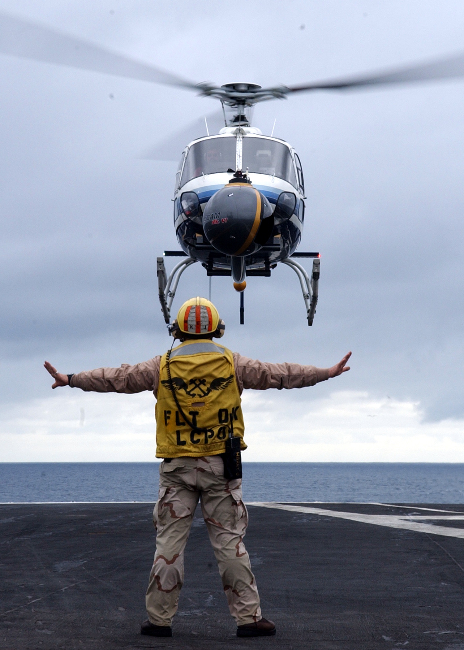 US Navy 040128-N-3241H-018 Chief Aviation Boatswain's Mate Glenn Harrison guides a commercial aerial filming helicopter safely to the flight deck aboard USS Carl Vinson (CVN 70)