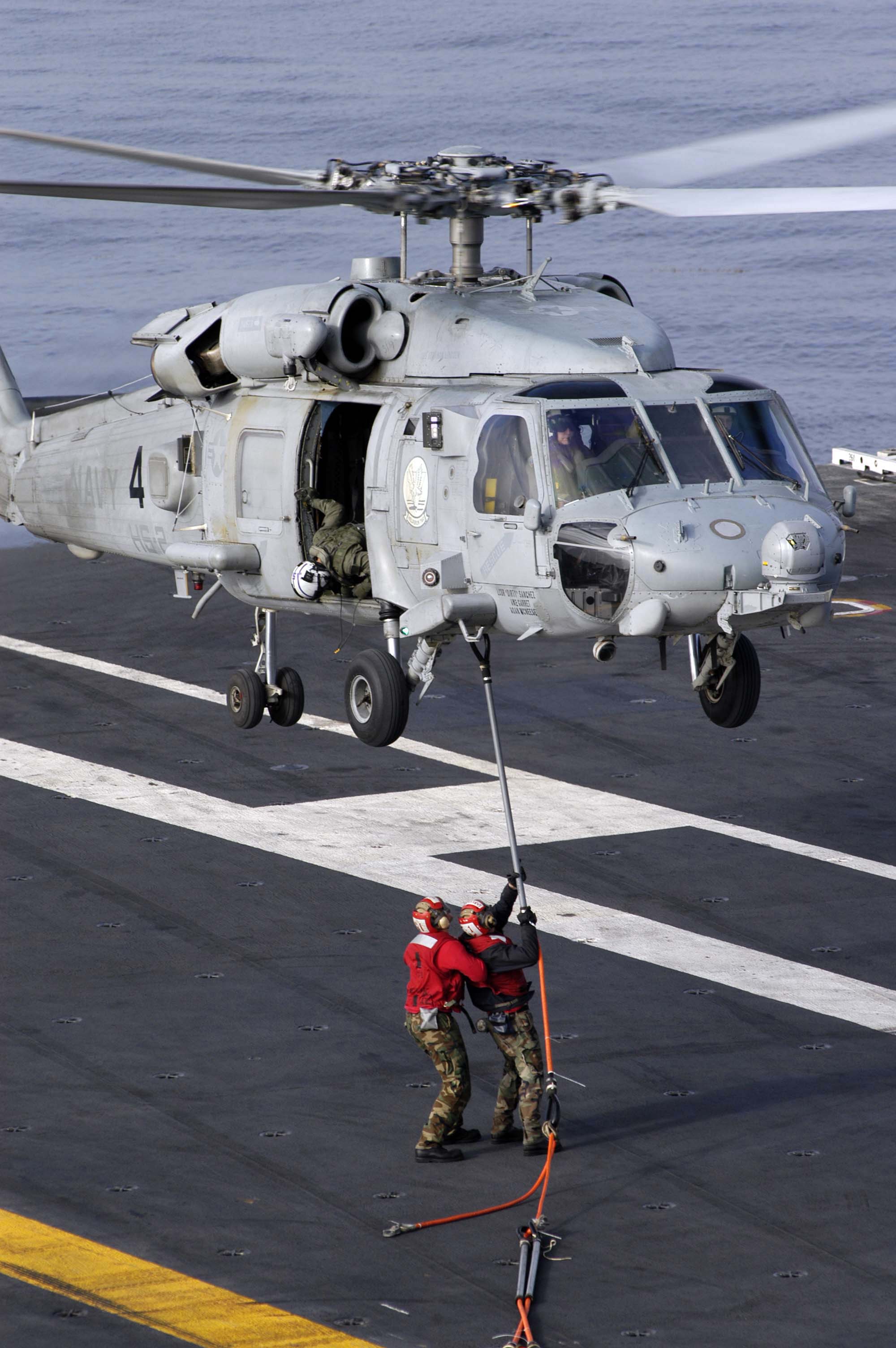US Navy 040825-N-9228K-015 Two Aviation Ordnancemen assigned to G-1 Weapons division aboard the aircraft carrier USS Abraham Lincoln (CVN 72) attach sling load assemblies to an HH-60H Seahawk