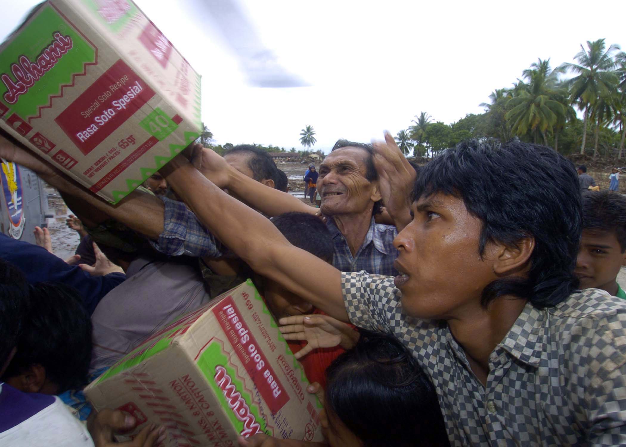US Navy 050108-N-9593M-145 Indonesian citizens reach for the food that is being unloaded from an SH-60F Seahawk helicopter