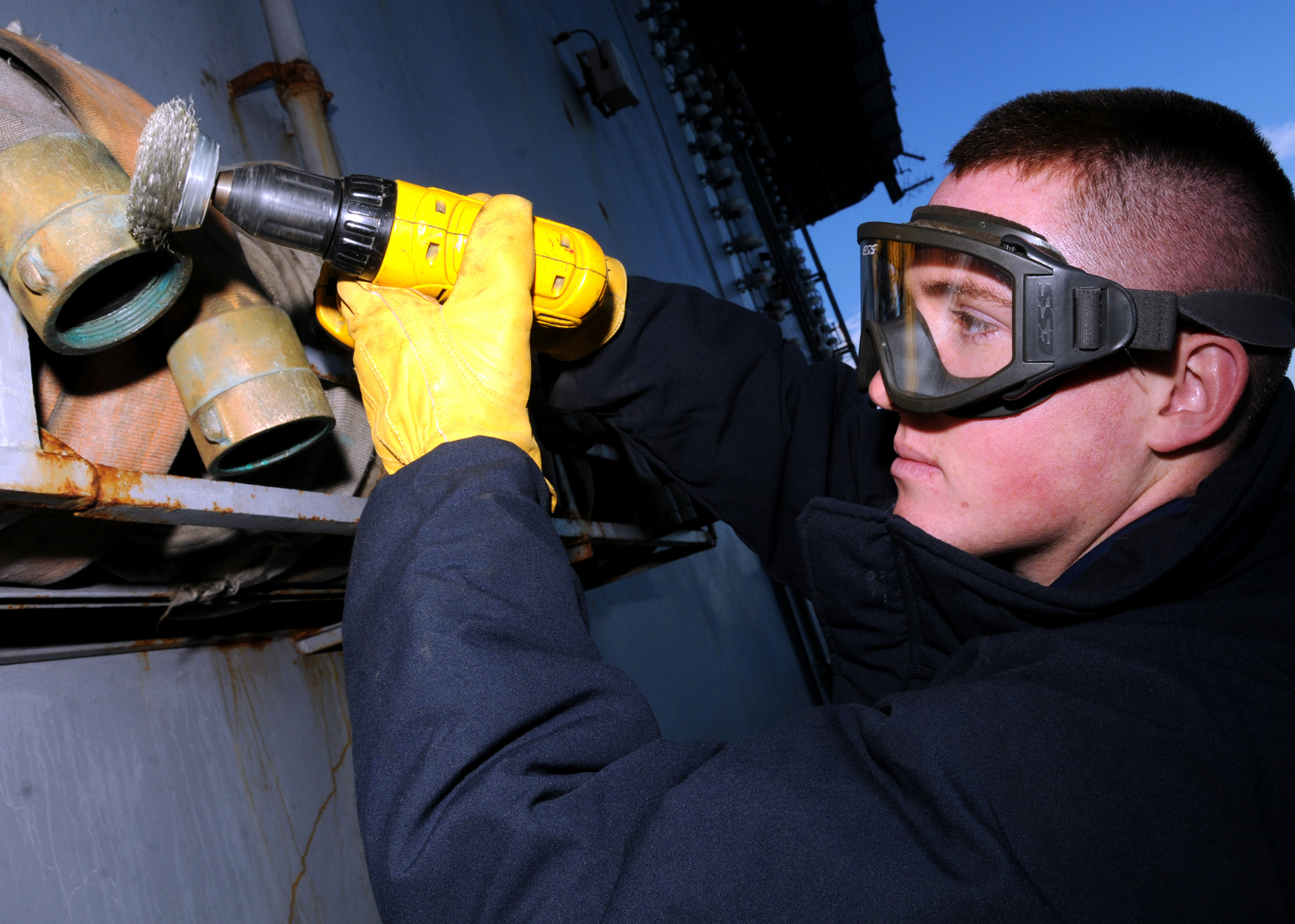 US Navy 081201-N-9898L-068 viation Boatswain's Mate Airman Mitchell Larson removes corrosion from a fire hose