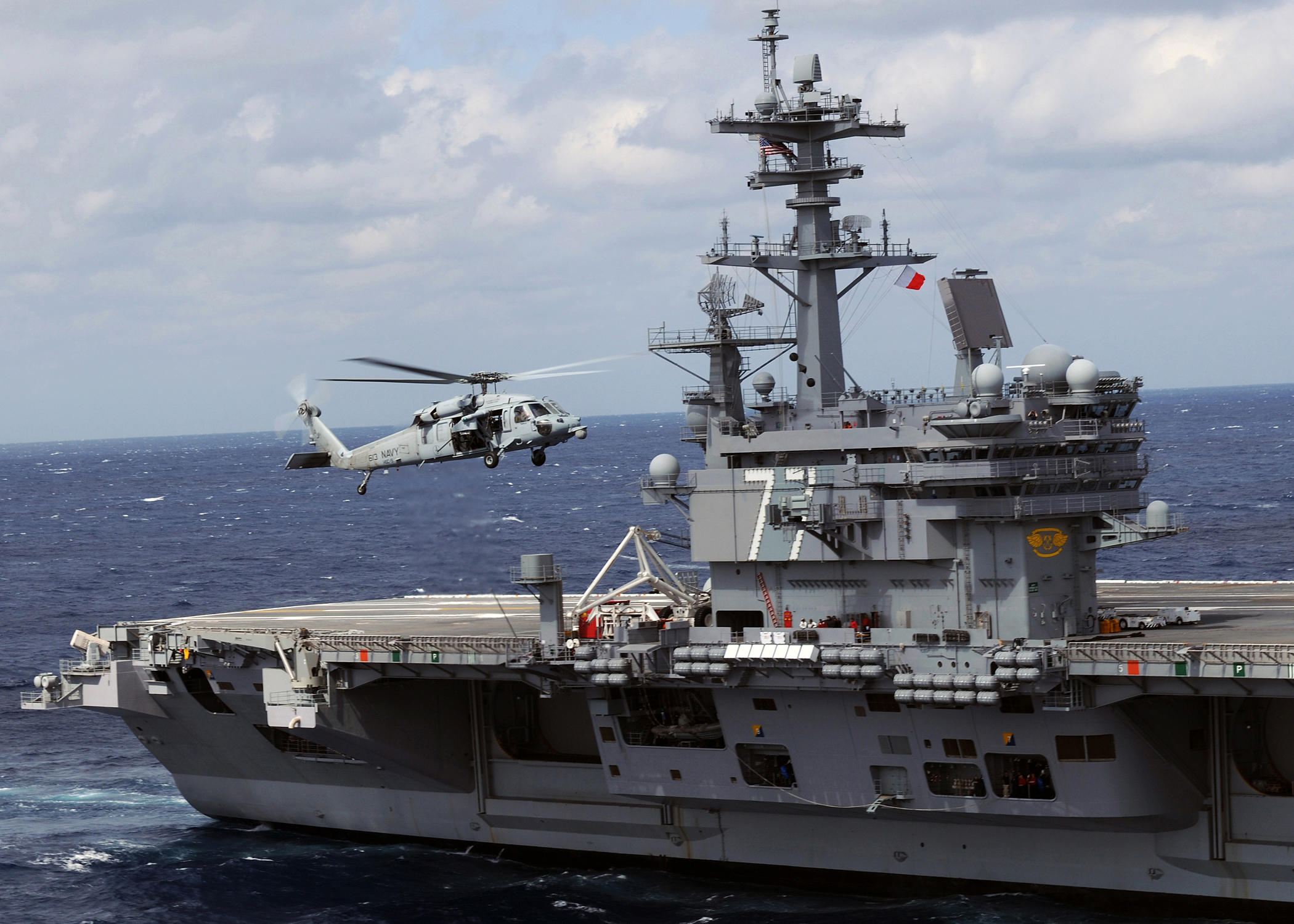 US Navy 100303-N-3885H-172 An MH-60S Sea Hawk helicopter flies alongside USS George H.W. Bush (CVN 77)