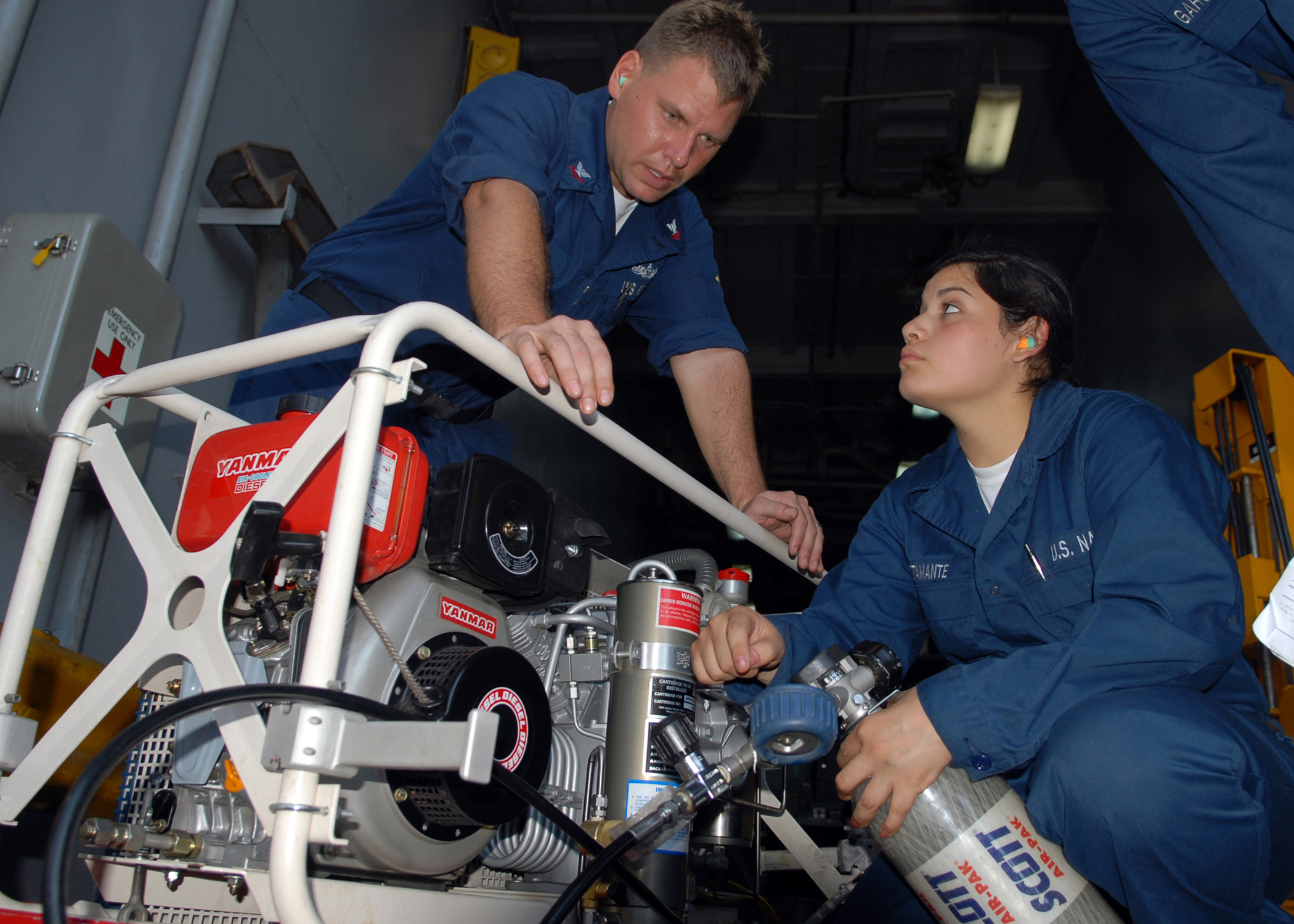 US Navy 100304-N-6692A-041 Damage Controlman 2nd Class Kevin L. Clark instructs Damage Controlman Fireman Recruit Marcela R. Bustamante on charging an oxygen bottle for self-contained breathing apparatus