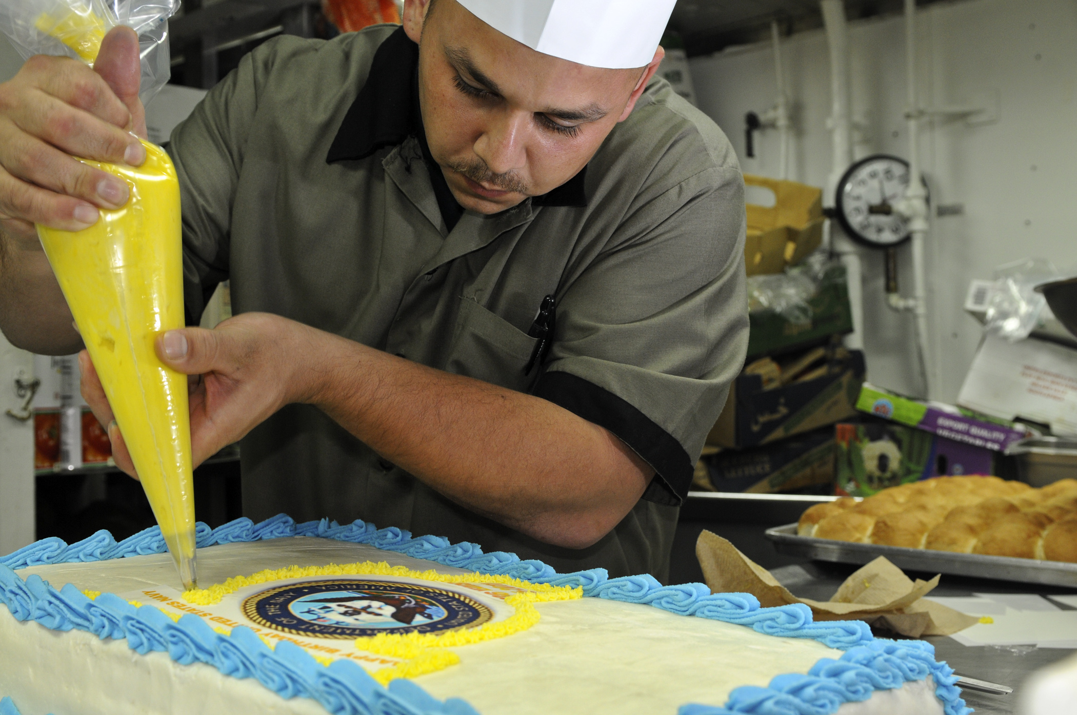 US Navy 111013-N-YM590-093 Culinary Specialist 2nd Class Daniel Lowen decorates a cake for the U.S. Navy's 236th birthday celebration aboard the gu