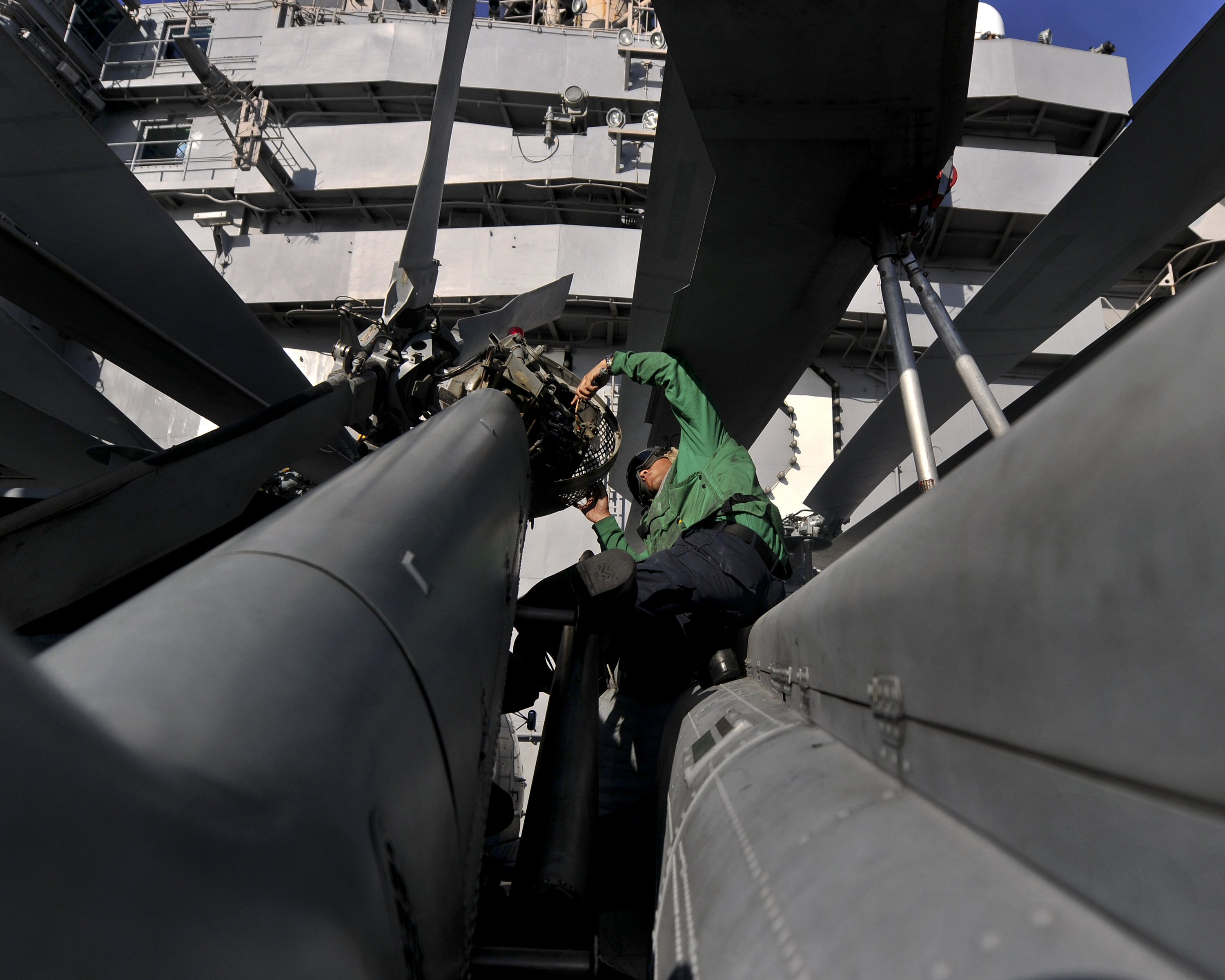 US Navy 120120-N-JN612-042 Aviation Electrician's Mate Airman Erik Gonzalez conducts maintenance on the rotor head of an MH-60S Sea Hawk helicopte