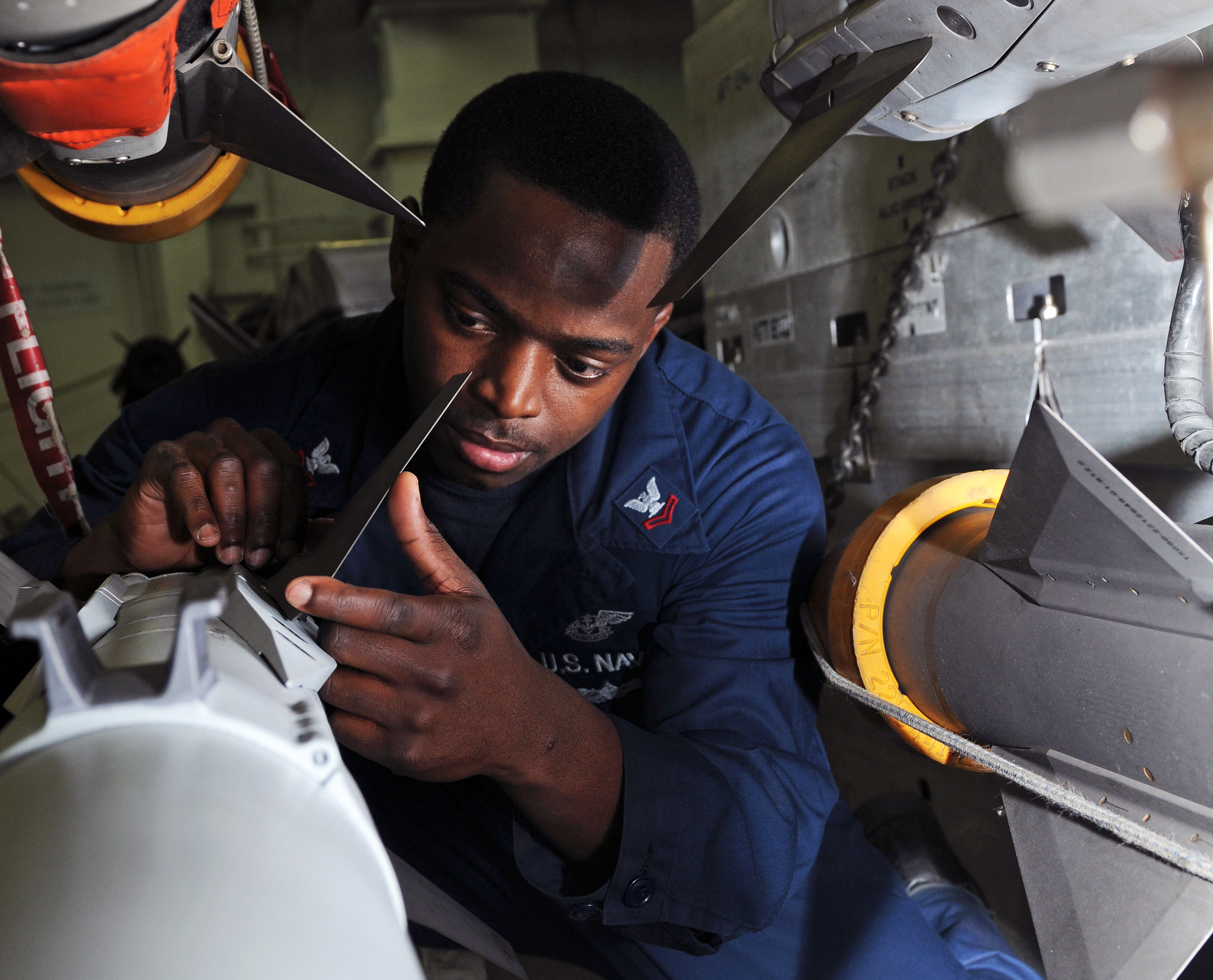 US Navy 120127-N-KQ416-101 Aviation Ordnanceman 2nd Class Timothy A. Flowers inspects the wing criteria on an AIM-9X Sidewinder missile aboard the 