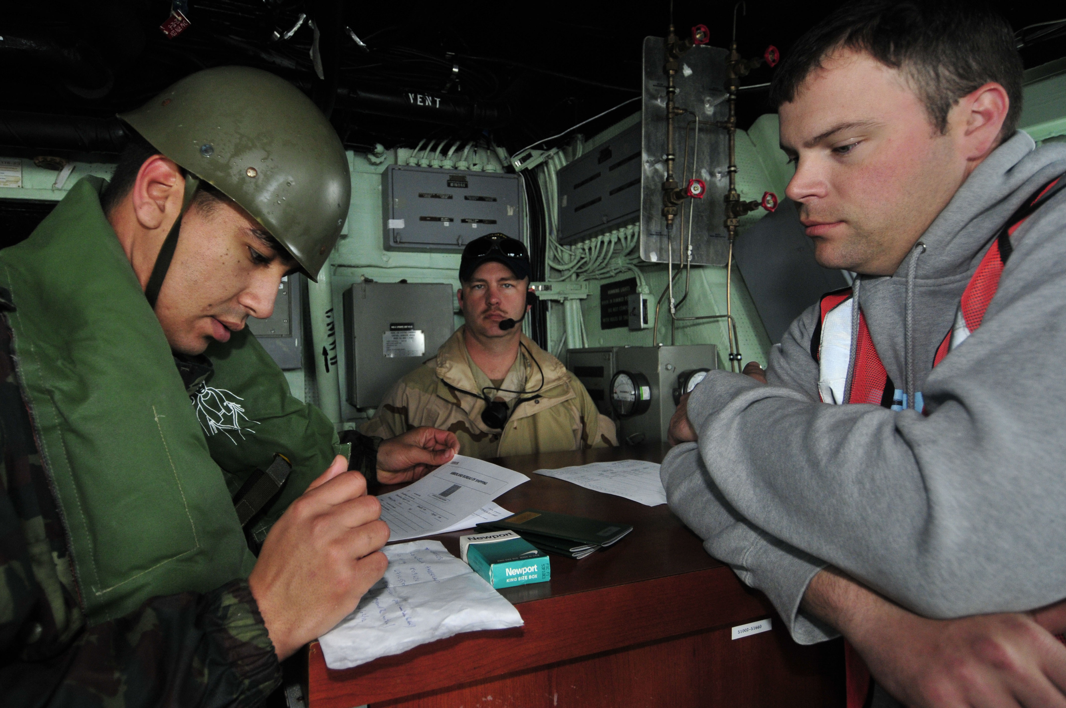 US Navy 120202-N-IZ292-079 Royal Moroccan Navy 1st Sgt. Hamid Karada checks the identification papers of Chief Gunner's Mate Sean Holmes, simulatin