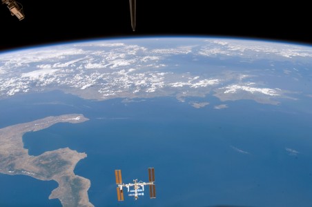 The Space Shuttle Endeavor crew captured this shot of the International Space Station (ISS) against the backdrop of Planet Earth. Pictured here the ISS is visible in front the Ionian Sea. The boot of Italy is visible on the left, while the western coastlines of Greece and Albania stretch across the top. The dorsal fin of the upside-down shuttle orbiter pokes into the very top of the image.