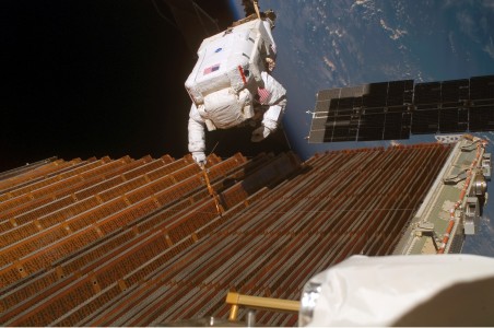 Original Description: ISS014-E-10084 (18 Dec. 2006) --- Astronaut Robert L. Curbeam Jr., STS-116 mission specialist, works with the port overhead solar array wing on the International Space Station's P6 truss during the mission's fourth session of extravehicular activity (EVA). European Space Agency (ESA) astronaut Christer Fuglesang (out of frame), mission specialist, worked in tandem with Curbeam, using specially prepared, tape-insulated tools, to guide the array wing neatly inside its blanket box during the 6-hour, 38-minute spacewalk.