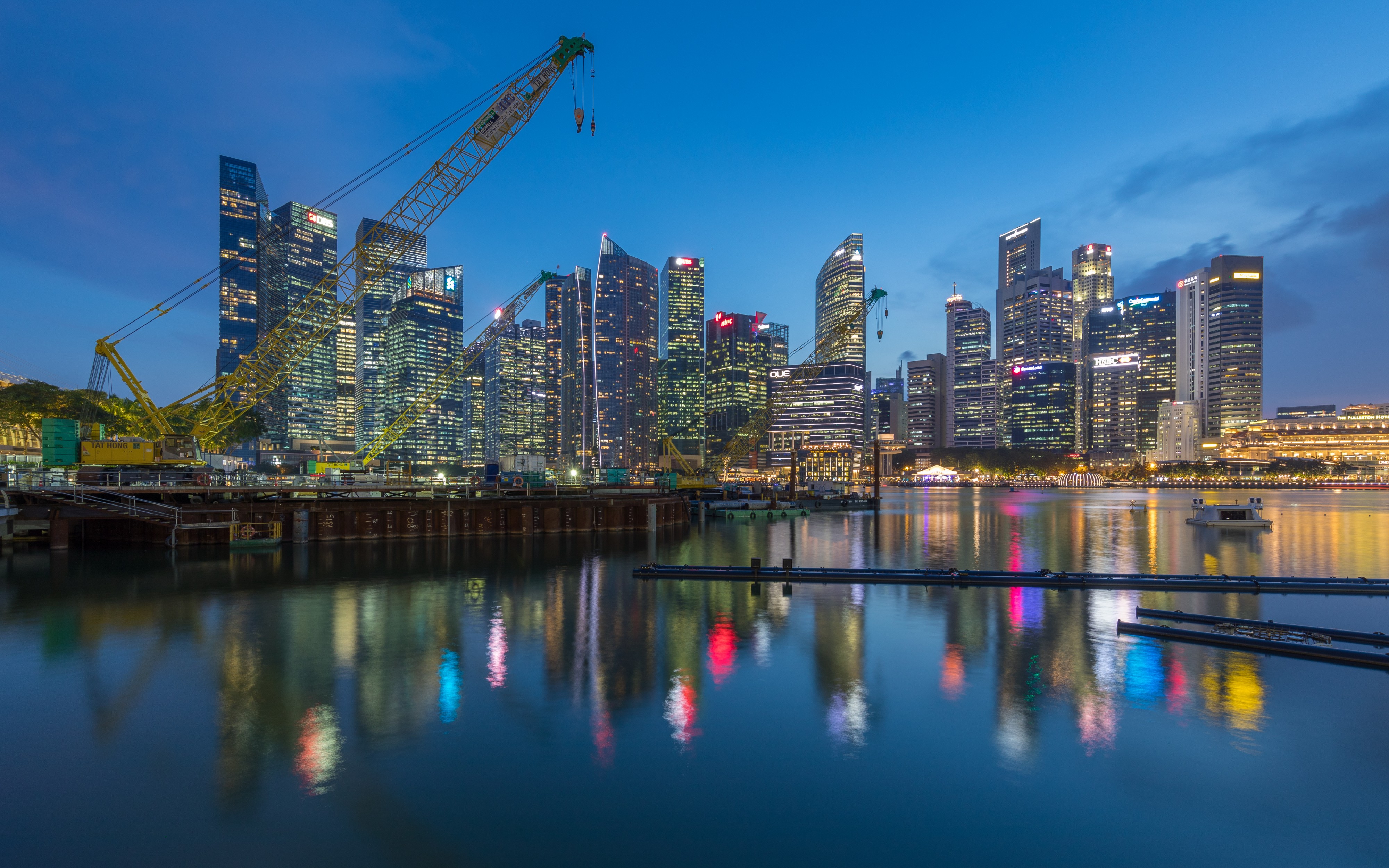 Crane and skylines of the Central Business District reflecting in the water at blue hour in Singapore