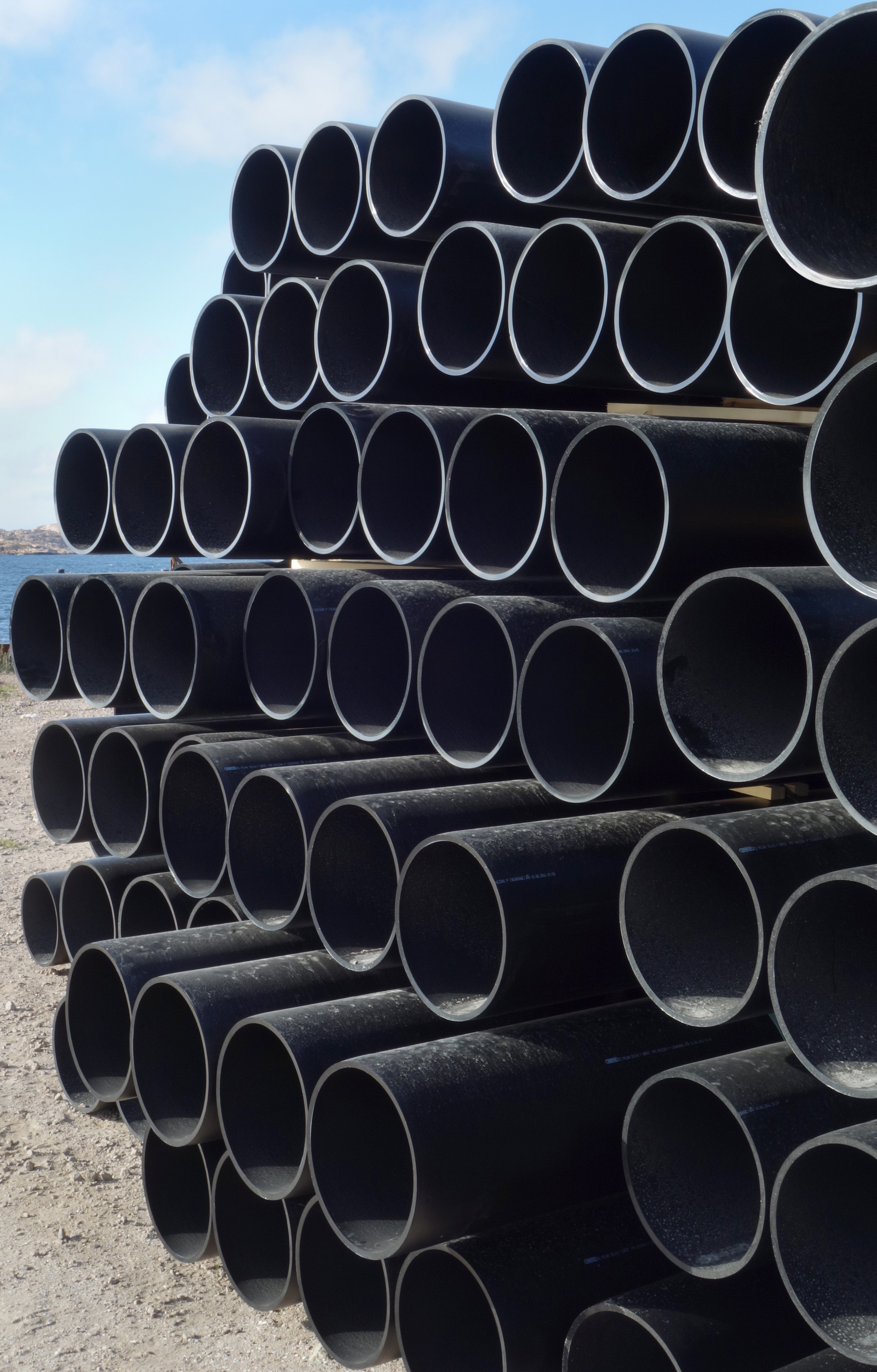Stack of large dusty black plastic pipes