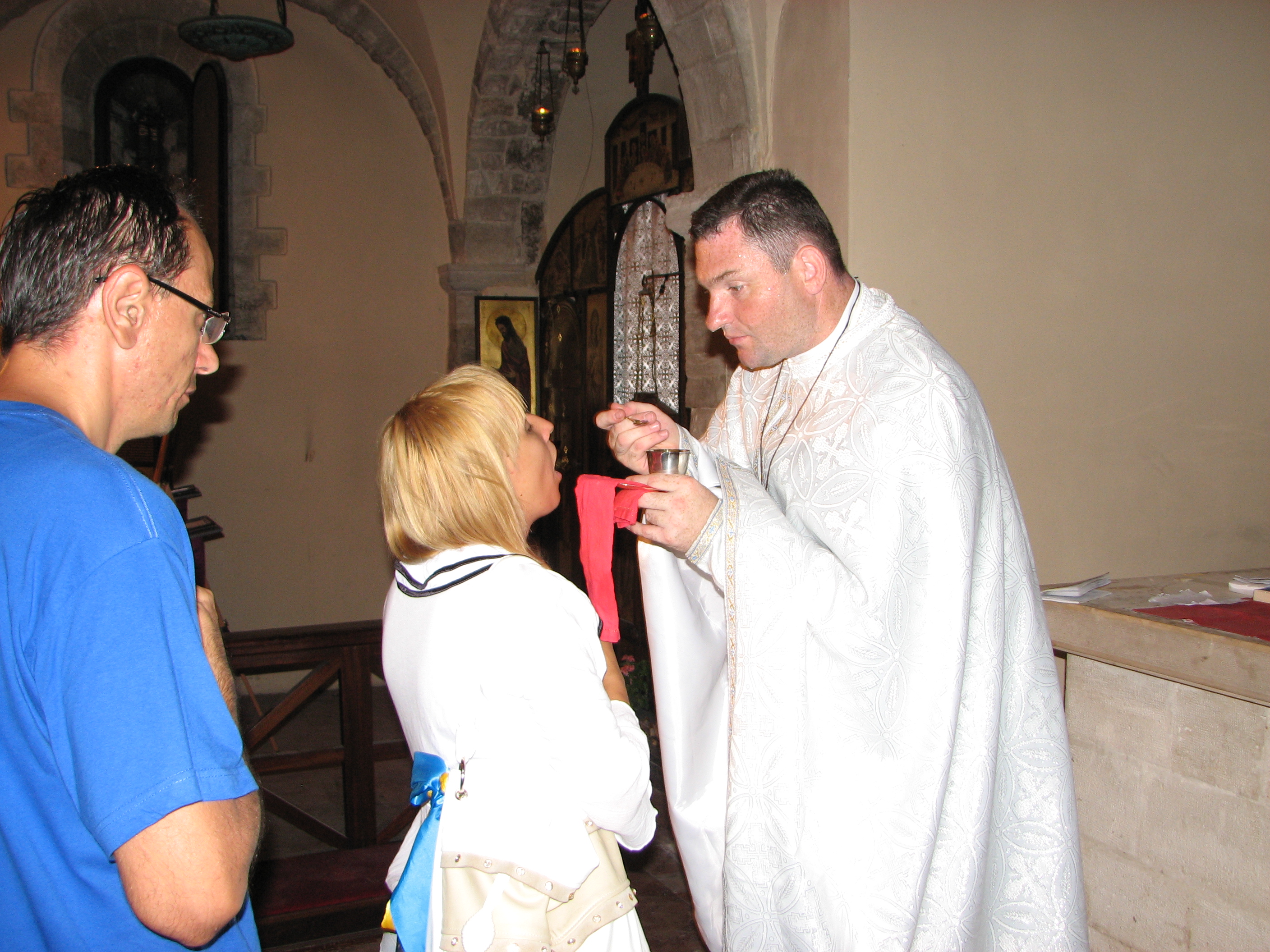 A young woman taking the Holy Communion from a Greek-Catholic priest, Italy, summer 2011