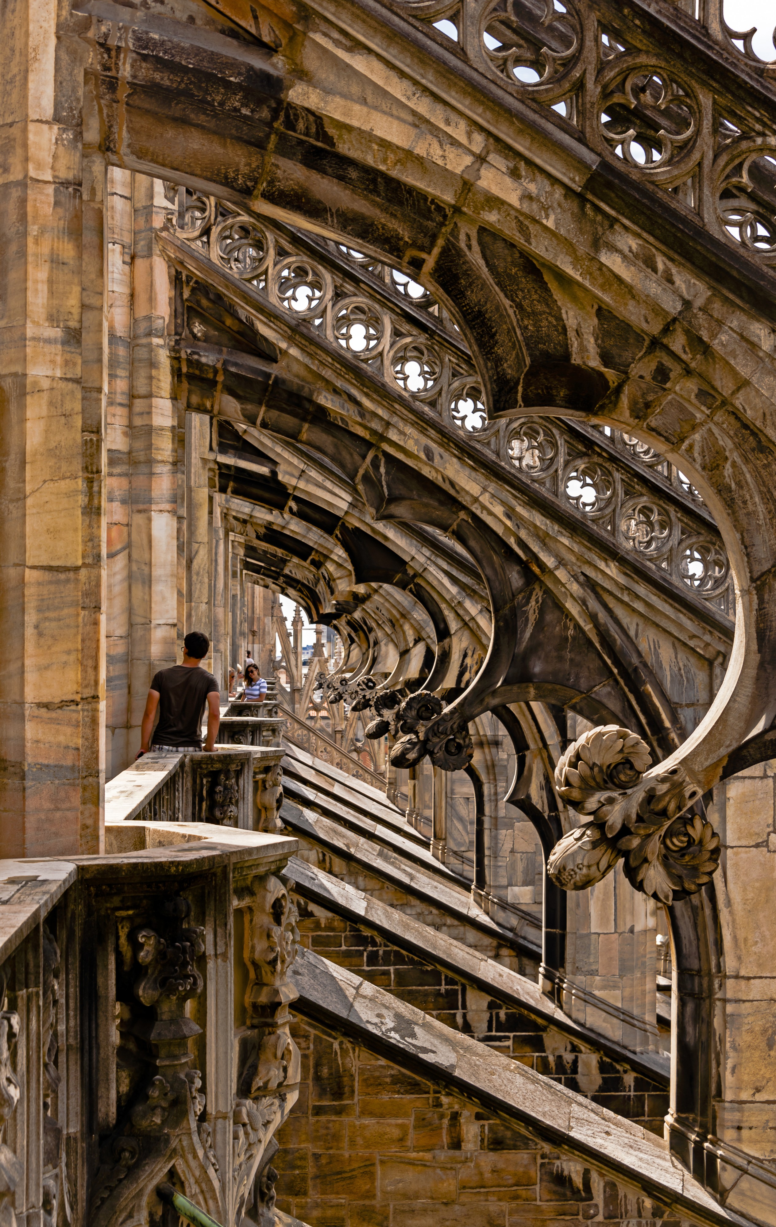 Tourists looking at flying buttresses on roof of Milan Duomo