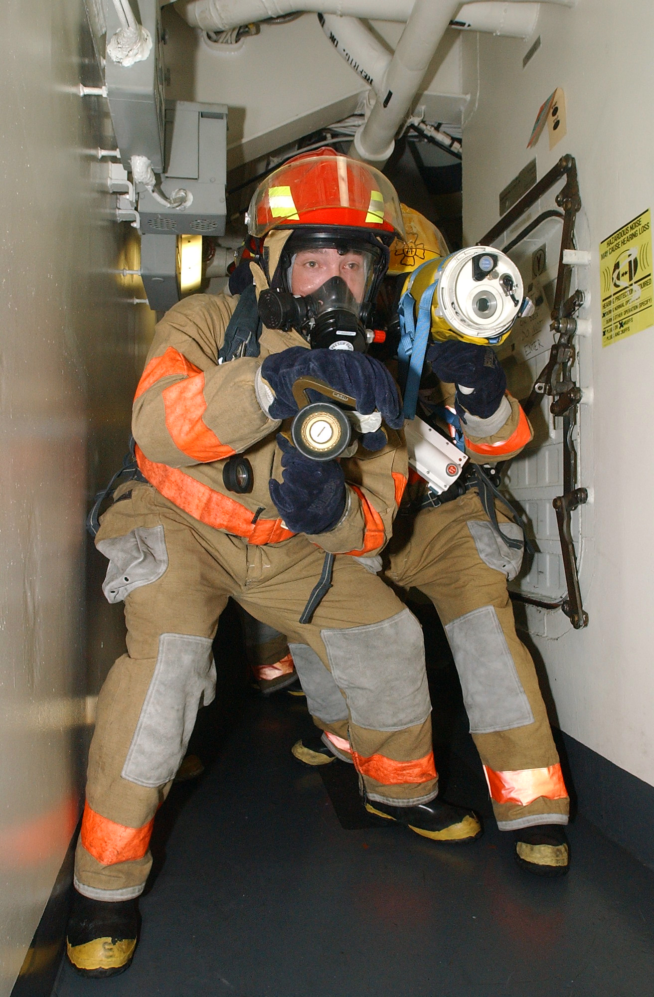 US Navy 040802-N-1513W-208 Damage Controlmen participating in a fire drill, use a Naval Firefighter Thermal Imaging (NFTI) device to simulate seeing through smoke in a workspace, during a drill aboard the aircraft carrier USS J