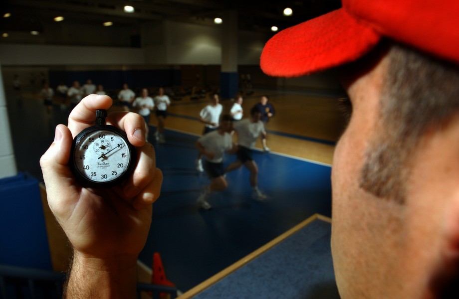 US Navy 030506-N-5862D-128 An instructor in the Freedom Hall athletic complex uses a stopwatch while recruits run a 1.5-mile track during a Physical Fitness Test (PFT)