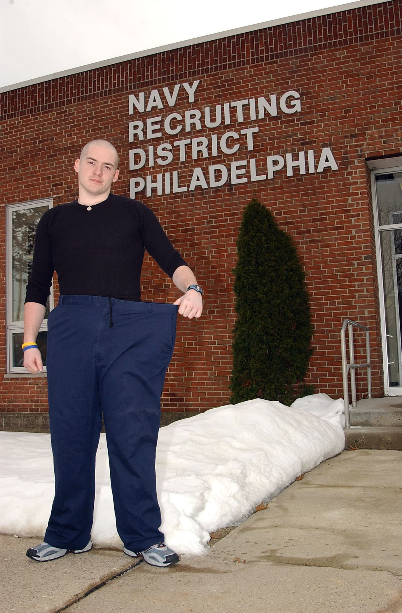 US Navy 050203-N-4729H-005 Navy Delayed Entry Program recruit Brian Connelly of Norwood, Pa., shows the pants he wore before he lost 175 lbs over the period of a year to join the U.S. Navy