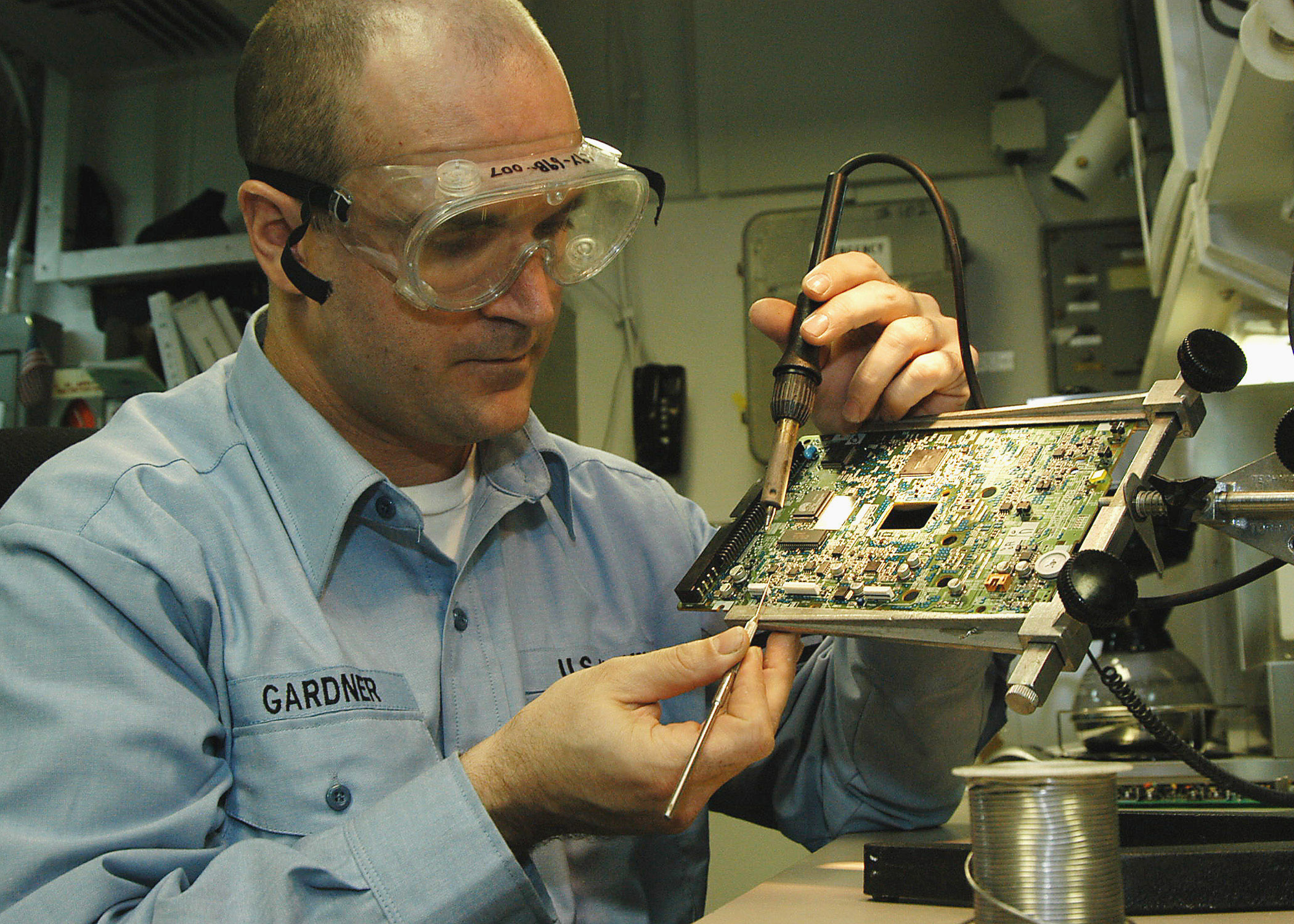 US Navy 040218-N-6278K-001 Aviation Electronics Technician 2nd Class Bill Gardner solders components on a printed circuit board