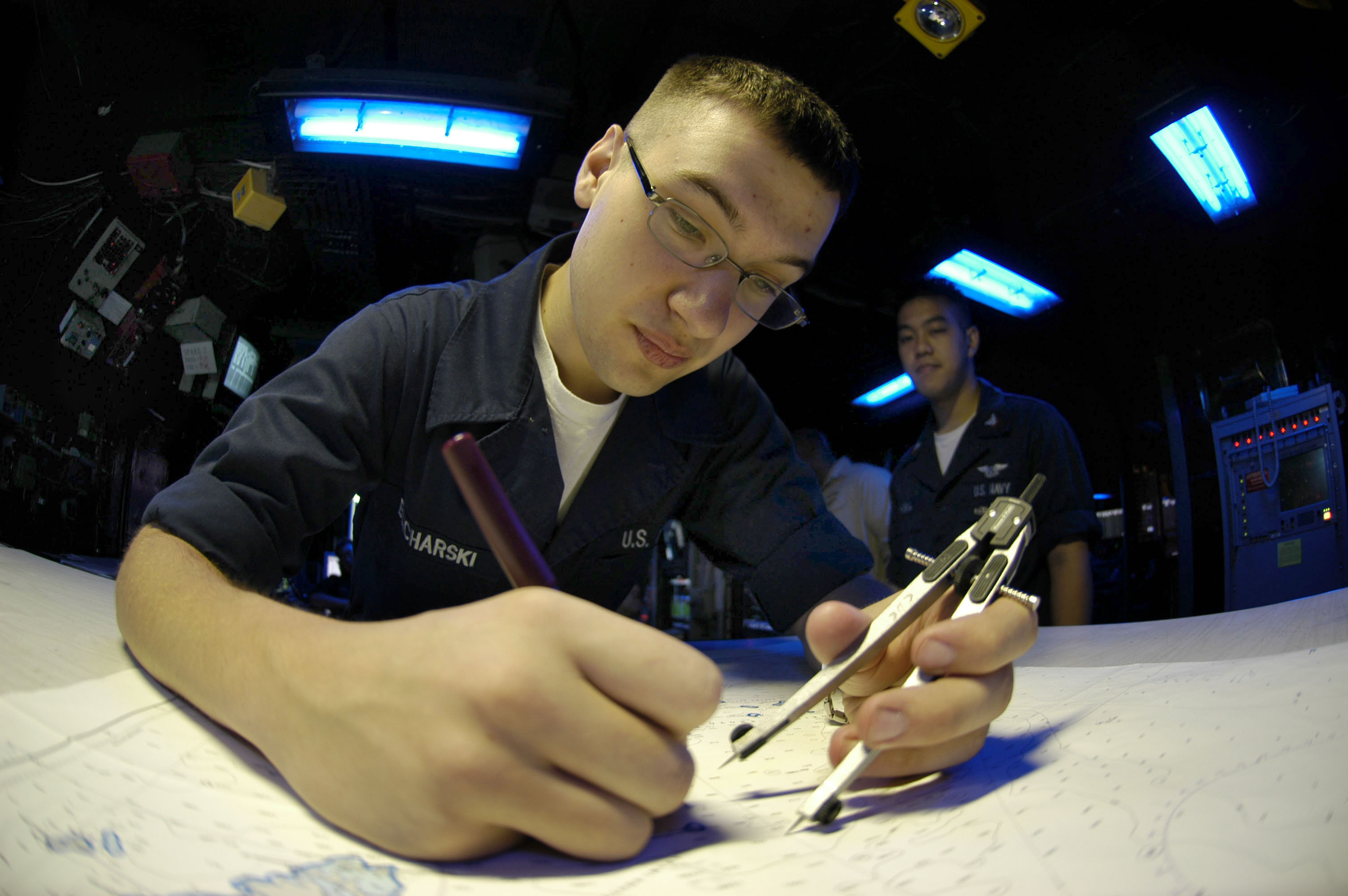 US Navy 050807-N-3136P-015 Operations Specialist Seaman Justin Blicharski of Lancaster, N.Y., plots the ship's position on a plotting table inside the Combat Direction Center