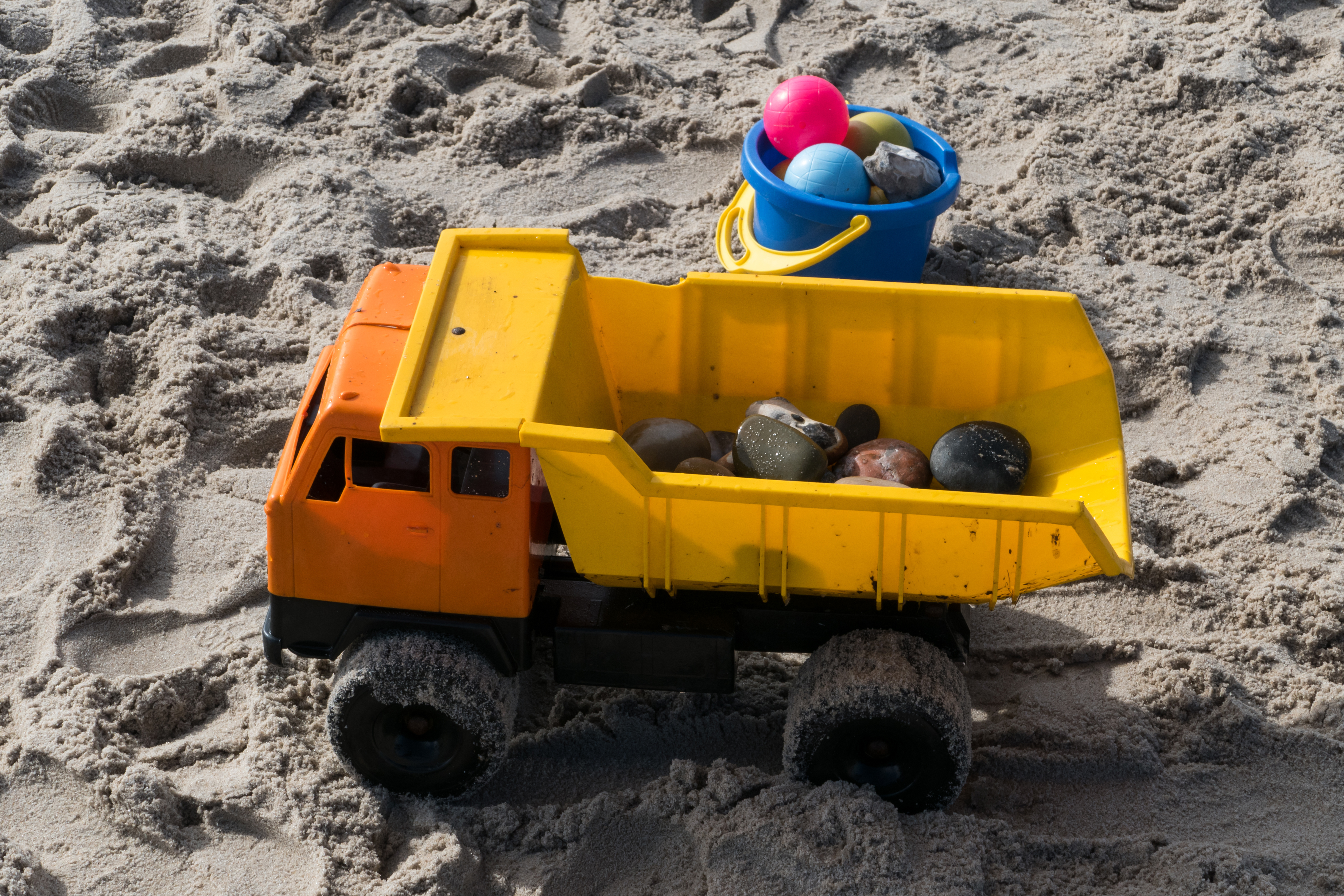 Plastic toy truck and pail in sand