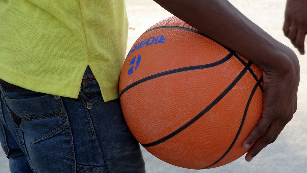 A person holding basket ball in his hand