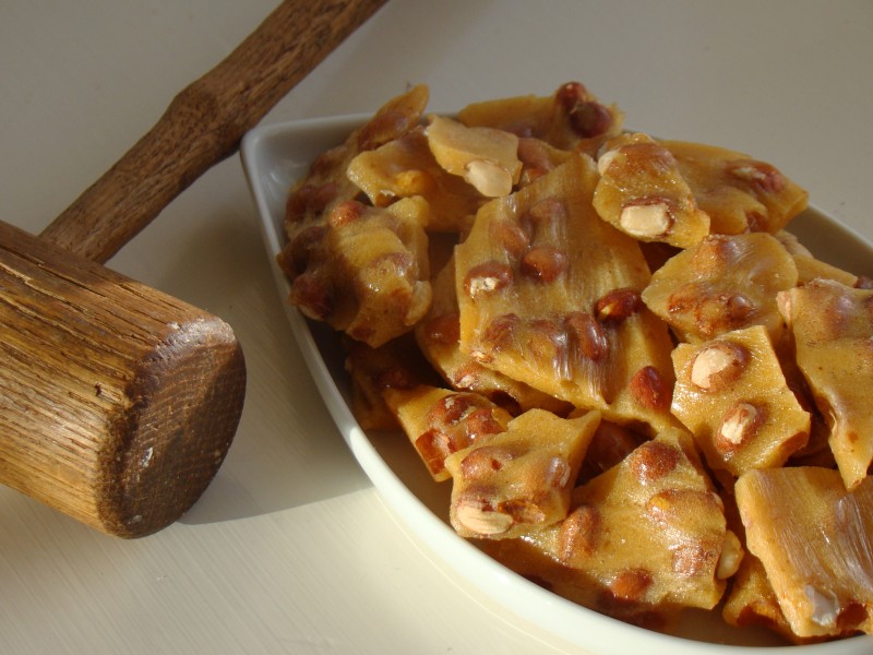 Golden peanut brittle with wooden hammer