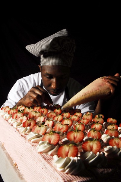 US Navy 070516-N-3729H-006 Culinary Specialist 3rd Class Ugene Ward applies frosting and fresh strawberries to one of many cakes made to serve approximately 5,000 Sailors and Marines 
